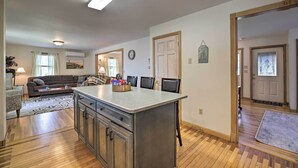 A spacious living area with a large kitchen island, wooden flooring, and a cozy seating arrangement. - Lake Champlain Home w/ Decks, Kayaks & Fire Pit! (Saint Albans City)