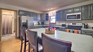A modern kitchen with grey cabinets, a central island, and a built-in microwave. - Lake Champlain Home w/ Decks, Kayaks & Fire Pit! (Saint Albans City)