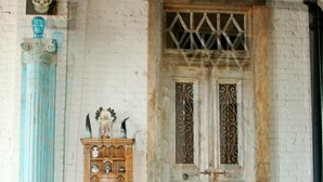 A rustic door with intricate metalwork, a wooden cabinet with glass doors, and a tiled floor. - Oversized loft (Denison)