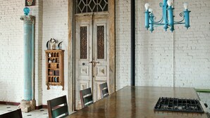 A dining area with a large table, chairs, a chandelier, a decorative shelf, and a door with intricate designs. - Oversized loft (Denison)
