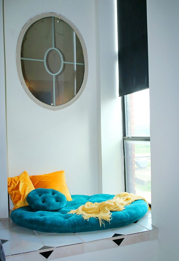 A window seat with a blue cushion, a yellow pillow, and a yellow blanket. - Oversized loft (Denison)