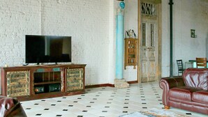 A living room with a television, a leather sofa, a patterned rug, and a tiled floor. - Oversized loft (Denison)