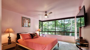 A bedroom with a bed, a ceiling fan, a TV mounted on the wall, and a window with a view of greenery. - Artsy Fun 5 minute walk to Parque Lleras  and Provenza (Medellín)