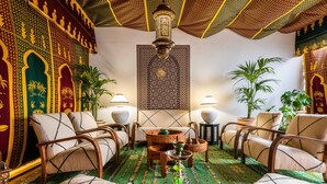 A traditional Moroccan interior with patterned walls, wooden furniture, and a hanging tapestry.