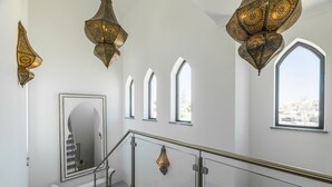 A staircase with a glass railing, ornate wall sconces, and a large mirror.