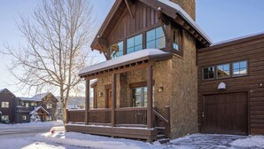 Une cabane en bois avec une façade en pierre, un porche et un garage.