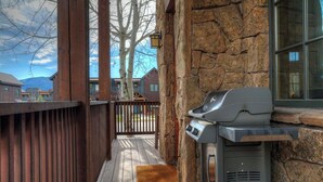 Une terrasse en bois avec un mur en pierre et un barbecue.