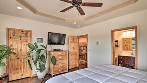 A bedroom with a large bed, wooden wardrobe, a television, and a ceiling fan.
