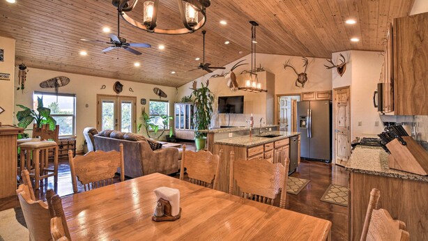 A spacious kitchen with wooden cabinets, a central island, and a dining area with wooden chairs and a table.