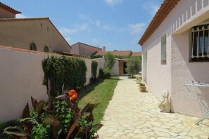 Stroll through the serene courtyard, surrounded by a low wall and lush greenery, leading to a simple, clean building entrance.