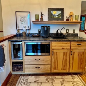 A kitchen with wooden cabinets, a built-in oven, a coffee maker, and a sink.