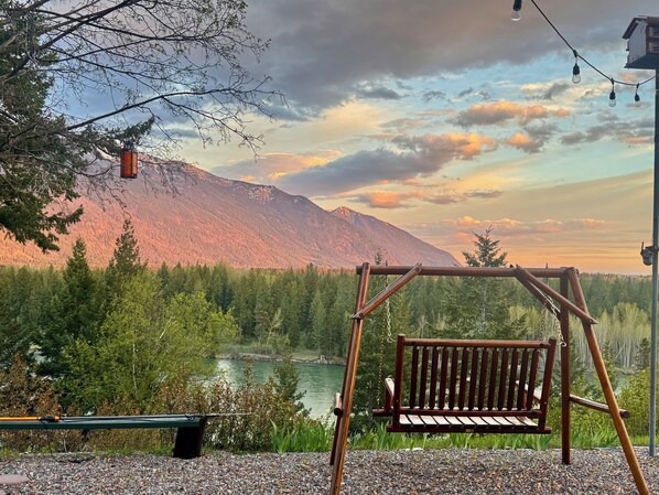 A wooden swing set near a lake with a mountain in the background.