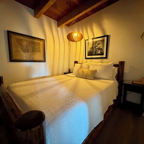 A bedroom with a bed, a map, and a tree picture on the wall.