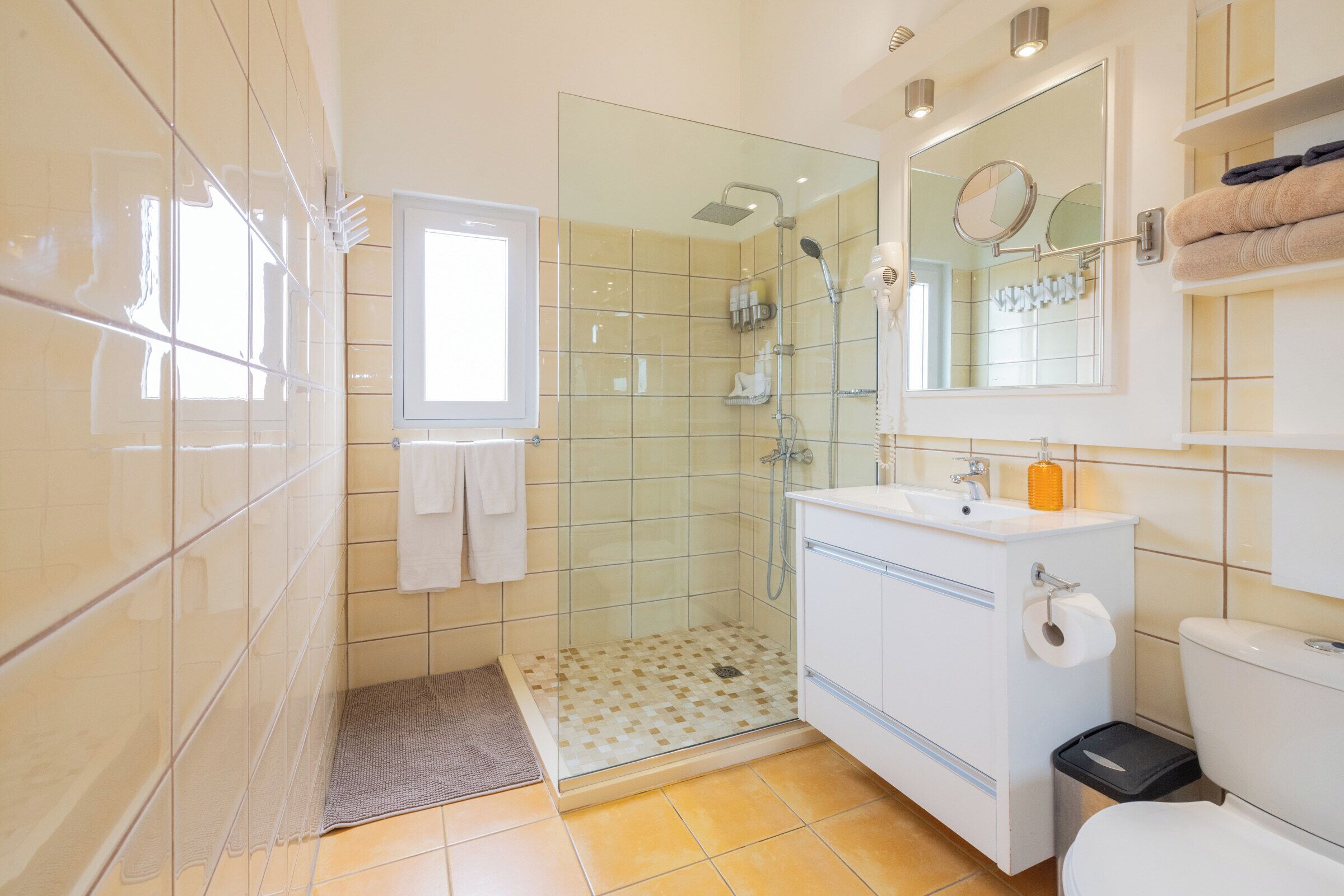 Un baño moderno con cabina de ducha de vidrio, un lavabo blanco y un inodoro.