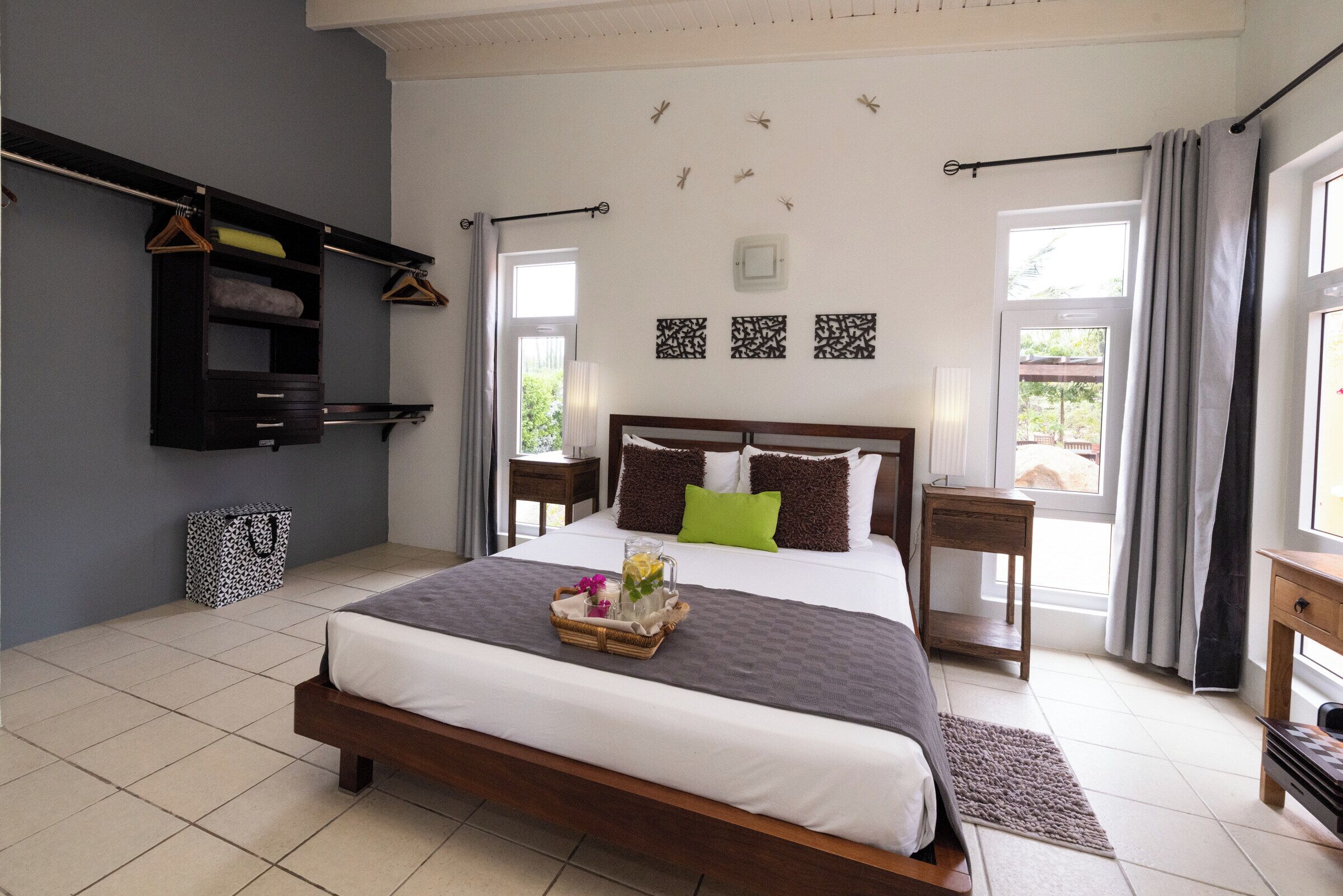 A neatly arranged bedroom with a large bed, a bedside table, a wardrobe, and a window with curtains.