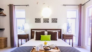 Un letto rifatto con cura, un vassoio con prodotti per la colazione, un cuscino verde e decorazioni a parete.