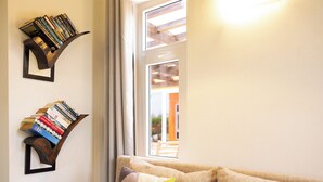 Ein Wohnzimmer mit einer Couch, zwei Bücherregalen und einem Fenster mit Vorhängen.