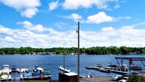 Uma marina com barcos atracados, um cais e uma vista ampla da água e da costa distante.