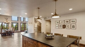 Una cocina amplia con una isla grande, armarios de madera e iluminación colgante.
