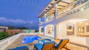 A rooftop pool area with lounge chairs and a hot tub.