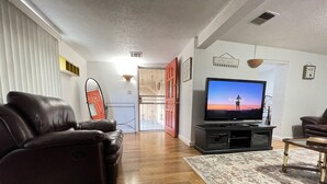 A living room with a leather sofa, a flat-screen TV, and a patterned rug.
