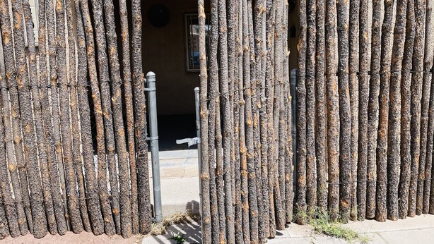 A rustic wooden gate with vertical slats and a metal bar in the center.