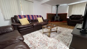 A living room with a brown leather sofa, a glass coffee table, and a patterned rug.