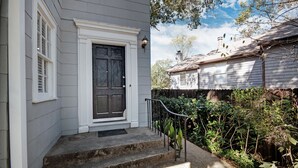 Una casa amb una porta principal fosca, adorns blancs i una petita escalinata de pedra que puja a la veranda.