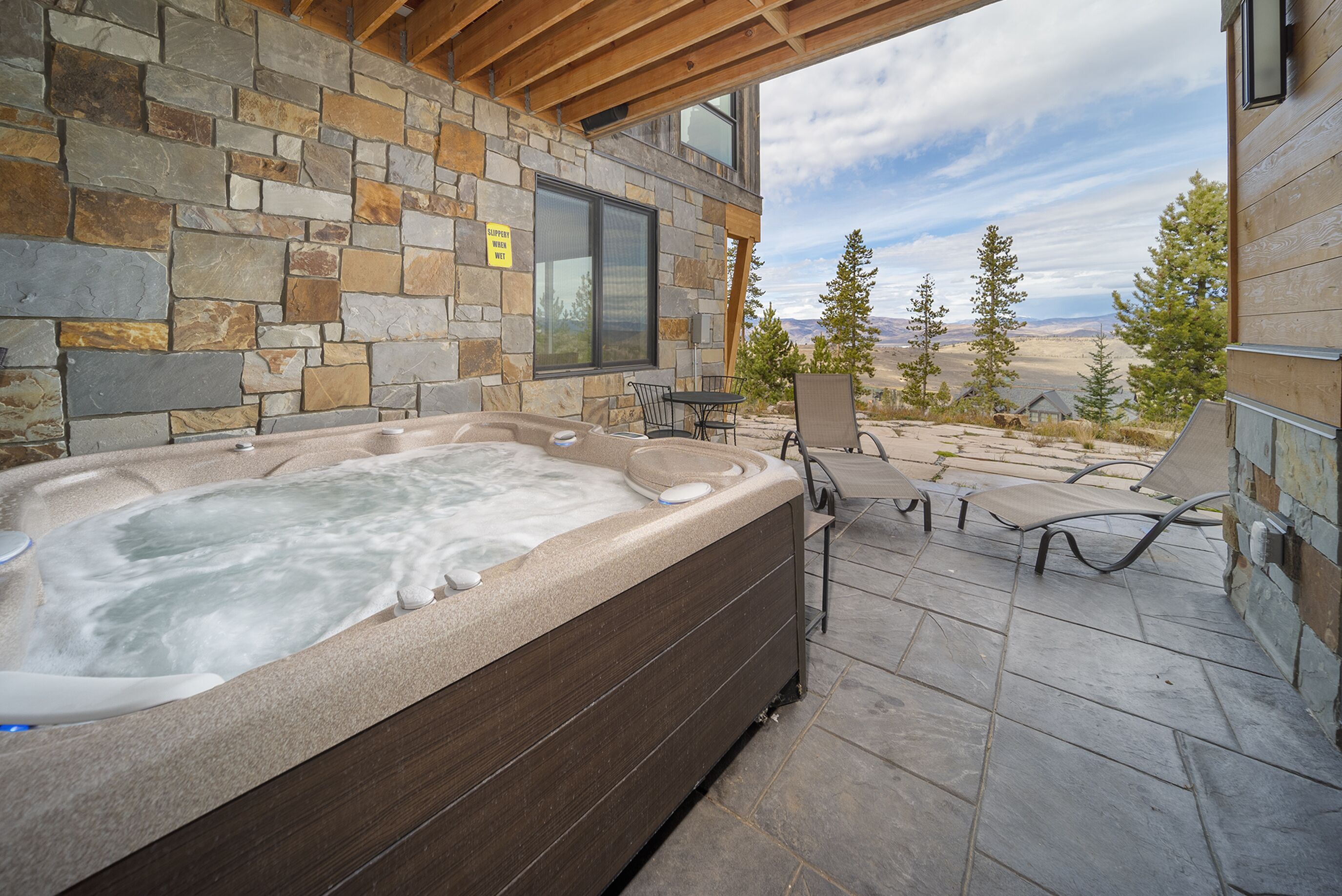 Un jacuzzi con paredes de piedra y un patio con sillas y una mesa.