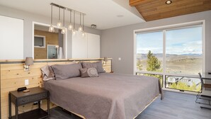 A modern bedroom with a large bed, a nightstand, a mirror, and a view of the outdoors. - Colorado's Coolest Ski In/Out Home - World Class Mtn. Biking, Hiking & Fishing (Granby)