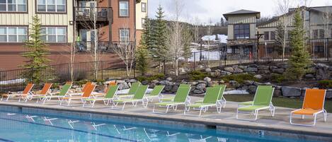 A swimming pool with lounge chairs and a building in the background.
