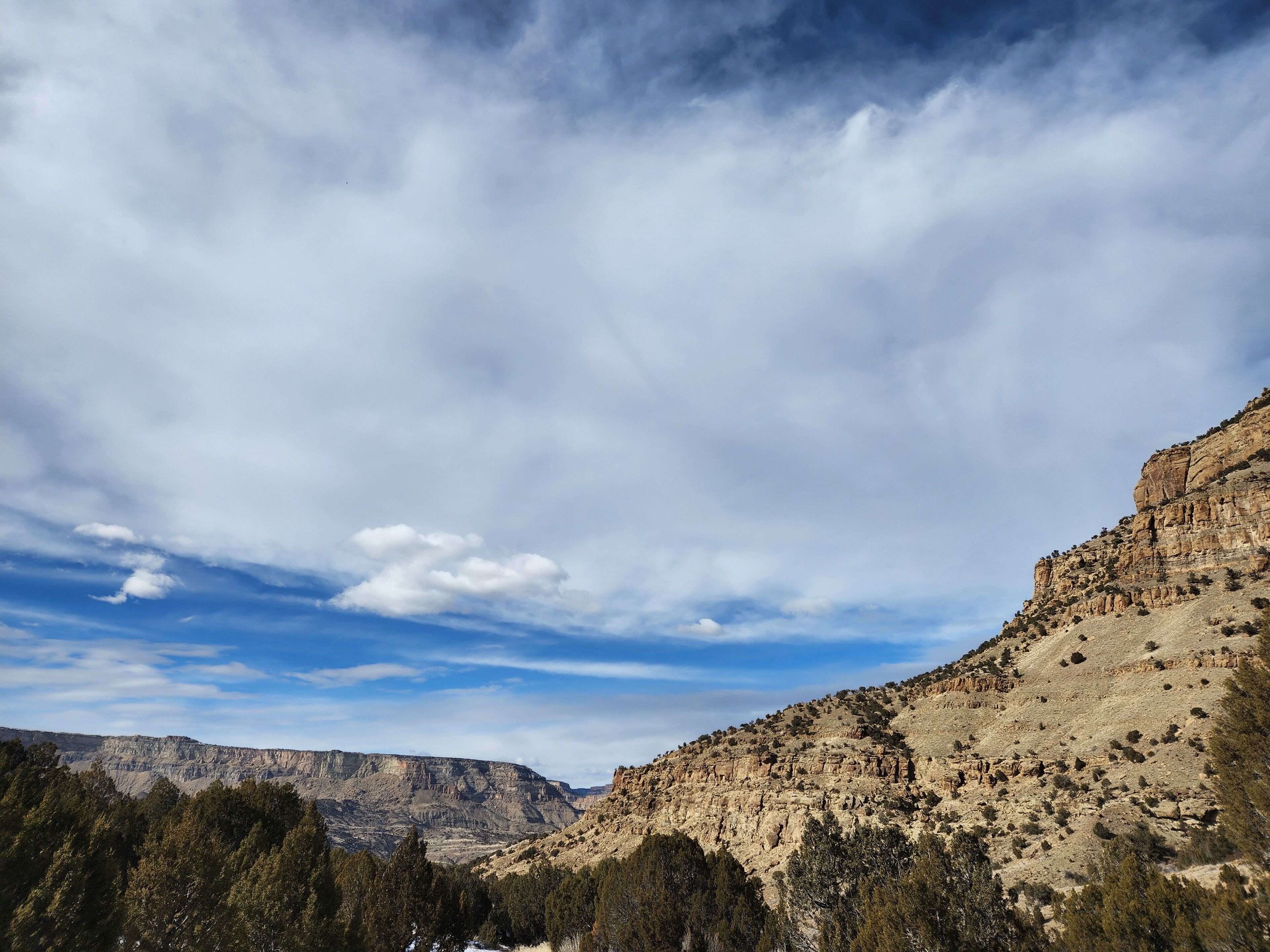 Un paysage montagneux, avec un ciel dégagé et une végétation clairsemée.