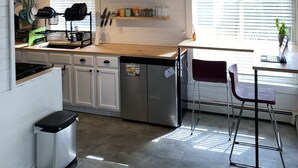 Een moderne keuken met houten plafond, inbouwapparatuur en een eethoek met een stoel en tafel.