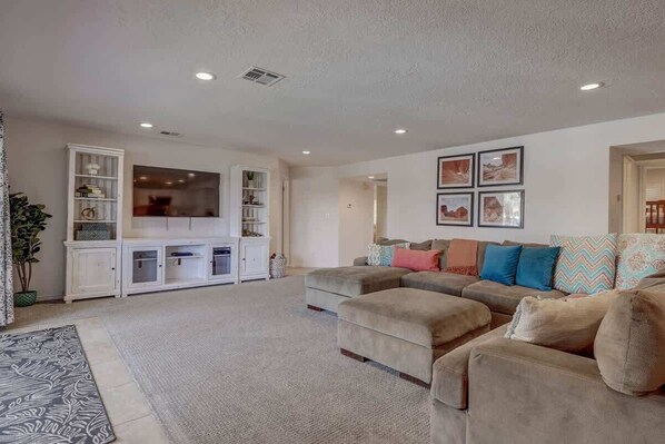 A living room with a sectional sofa, a flat-screen TV, and a white entertainment unit. - Las Palmas Resort #1620 | All-Inclusive Amenities (Saint George)