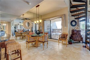 Enjoy dining and relaxation in this elegant space with a large dining table, comfortable seating area, and staircase to an upper level.