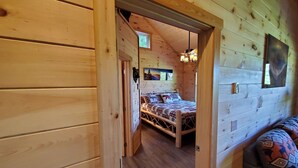 Una camera in una baita di legno con un letto, una finestra e una televisione a parete.