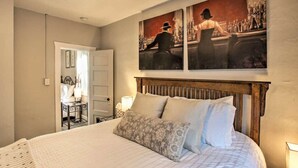 Une chambre à coucher avec un grand lit, une tête de lit en bois et deux tableaux accrochés au-dessus du lit.