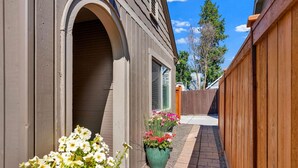 Un immeuble résidentiel doté d’un patio couvert, d’une clôture en bois et de plantes en pot.