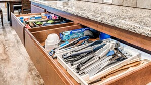Una cucina con un piano di lavoro in granito, lavastoviglie integrata e un organizer in legno per utensili da cucina.