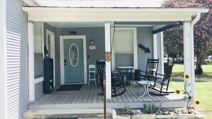 Une véranda avec une table et des chaises, une porte et un petit jardin agrémenté de tournesols.