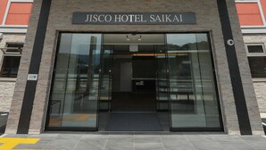 Exterior del HOTEL JISCO SAIKAI, con fachada moderna, gran entrada de vidrio y un letrero destacado sobre las puertas.