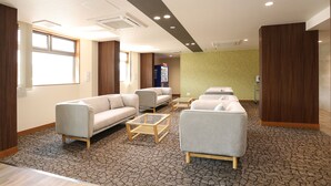 Un moderno vestíbulo de hotel con sofás, un mostrador de recepción y una alfombra estampada.