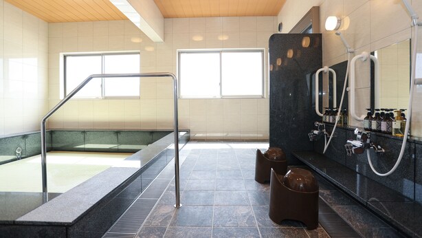 Un baño moderno con cabina de ducha de vidrio, un espejo grande y un tocador con varios lavamanos.
