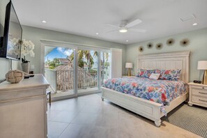A bedroom with a bed, a nightstand, a dresser, a ceiling fan, and a view of the outside. - P18 - Spectacular 4 bedroom home with dockage and oversized private pool in Key Colony! (Key Colony Beach)