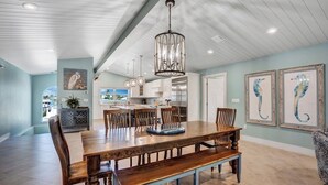 A spacious dining area with a large wooden table, benches, and a hanging light fixture. - P18 - Spectacular 4 bedroom home with dockage and oversized private pool in Key Colony! (Key Colony Beach)