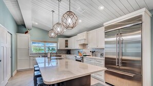 A spacious kitchen with a large island, stainless steel appliances, and pendant lighting. - P18 - Spectacular 4 bedroom home with dockage and oversized private pool in Key Colony! (Key Colony Beach)