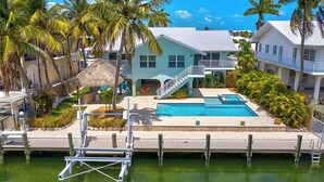 A resort with a swimming pool, a dock, and a thatched-roof structure. - P18 - Spectacular 4 bedroom home with dockage and oversized private pool in Key Colony! (Key Colony Beach)