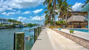 A waterfront hotel with a wooden dock, a pool area, and a thatched-roof building. - P18 - Spectacular 4 bedroom home with dockage and oversized private pool in Key Colony! (Key Colony Beach)