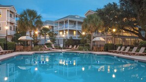 A swimming pool surrounded by lounge chairs and umbrellas, with multi-story buildings in the background. - Edisto Beach 1BR w/Beach Access (Edisto Island)