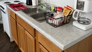 A kitchen with wooden cabinets, a stainless steel sink, a stove, and a coffee maker. - Authentic Native American Hogan Experience near Chaco Cultural Historical Park (Counselor)